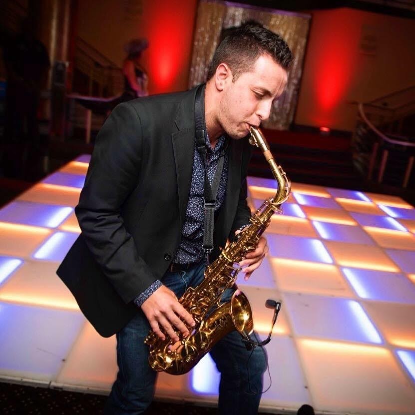 A person playing a saxophone in a well lit Venue