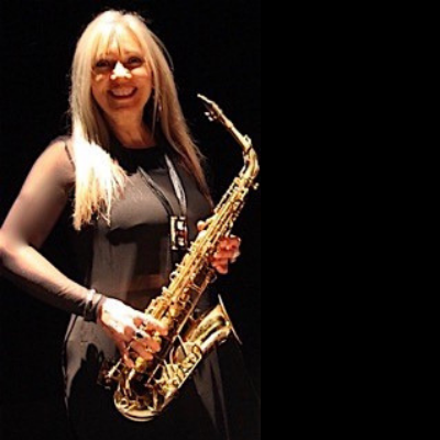 A person smiling for a photo holding a saxophone