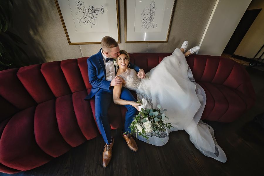 A person in a suit and person on a wedding dress sitting on a couch