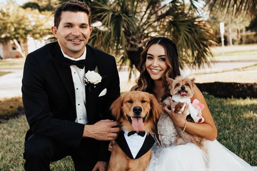 A person in a suit and person in a wedding dress and a dog in a tuxedo