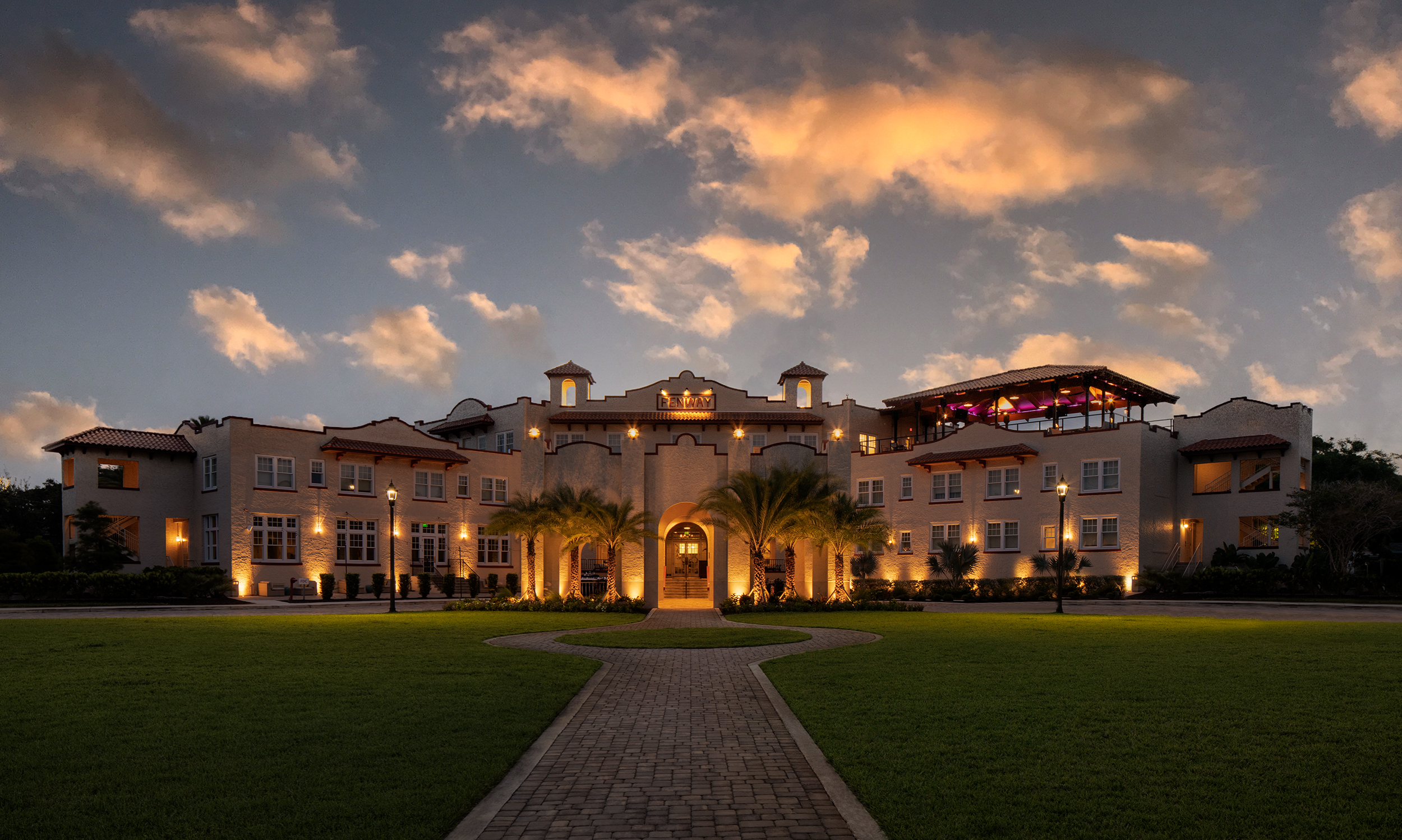 A large building with lights and a huge lawn space