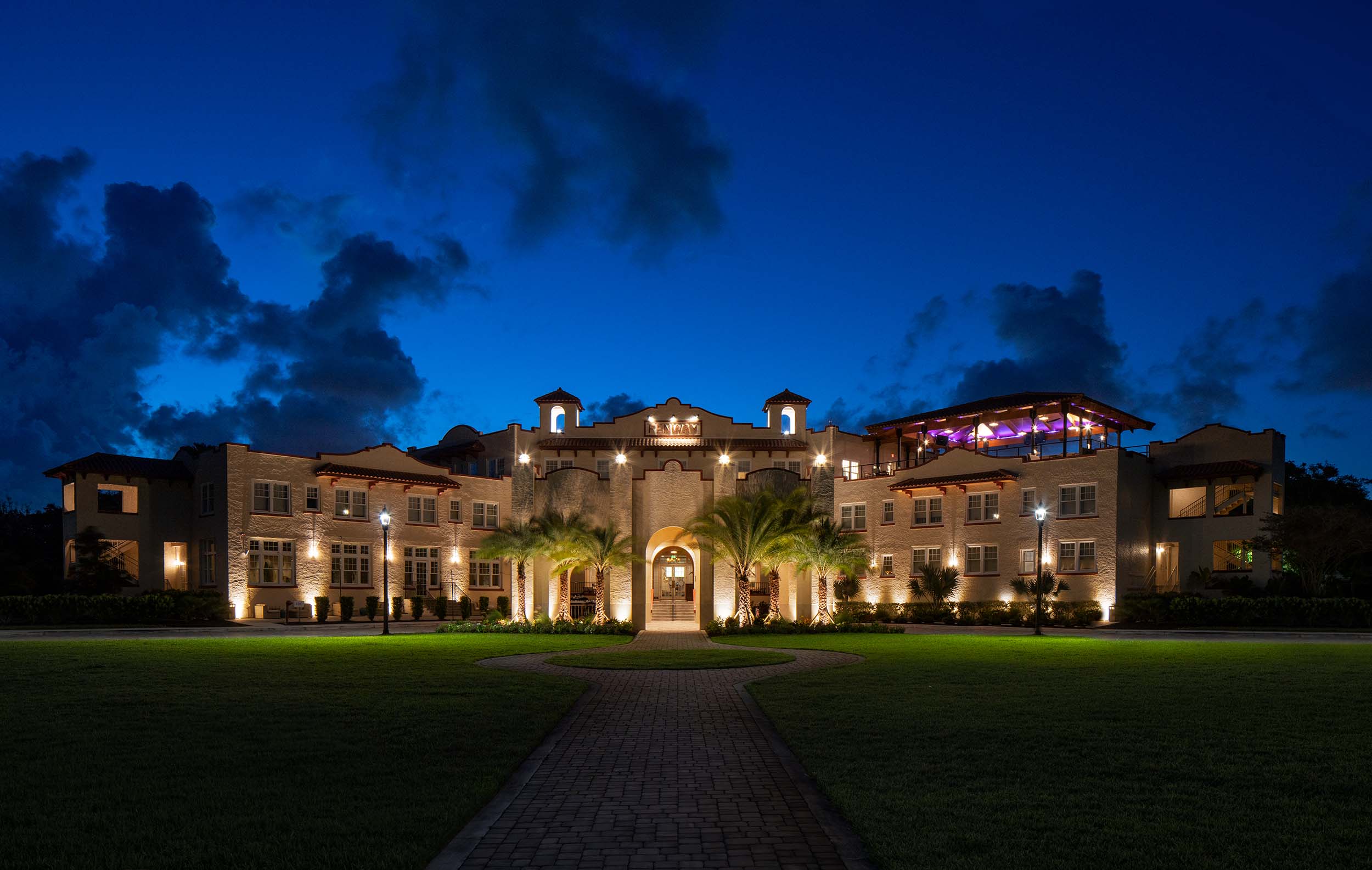 A large building with lights at night with a huge lawn